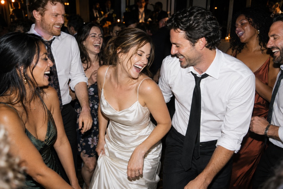 Friends and newlyweds laughing together on the dance floor
